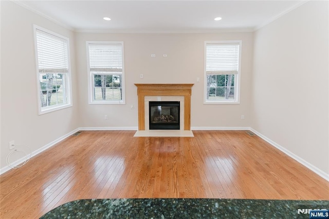 unfurnished living room featuring ornamental molding, hardwood / wood-style floors, and a healthy amount of sunlight