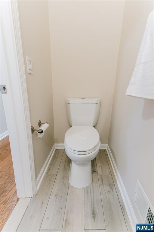 bathroom with toilet, baseboards, visible vents, and wood finished floors