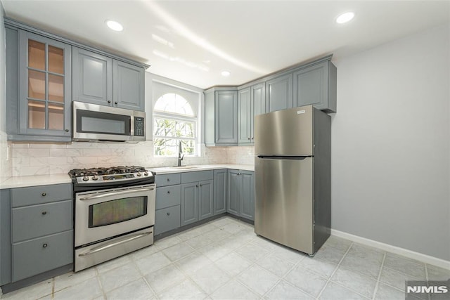 kitchen with light countertops, appliances with stainless steel finishes, decorative backsplash, and gray cabinetry