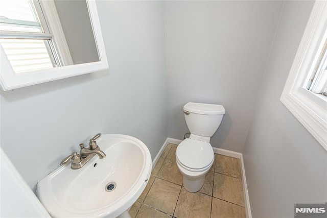 bathroom with plenty of natural light, a sink, toilet, and baseboards