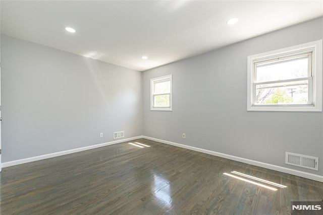 spare room with dark wood-type flooring, recessed lighting, visible vents, and baseboards