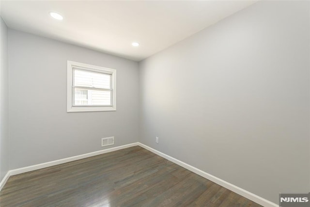 empty room with dark wood-type flooring, recessed lighting, visible vents, and baseboards