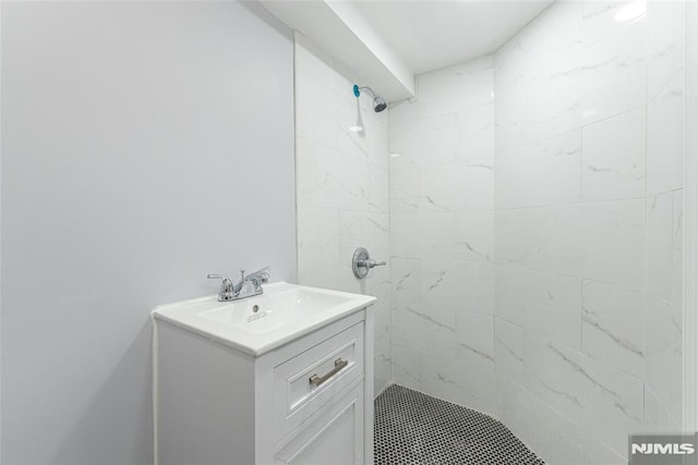 full bath with tiled shower and vanity