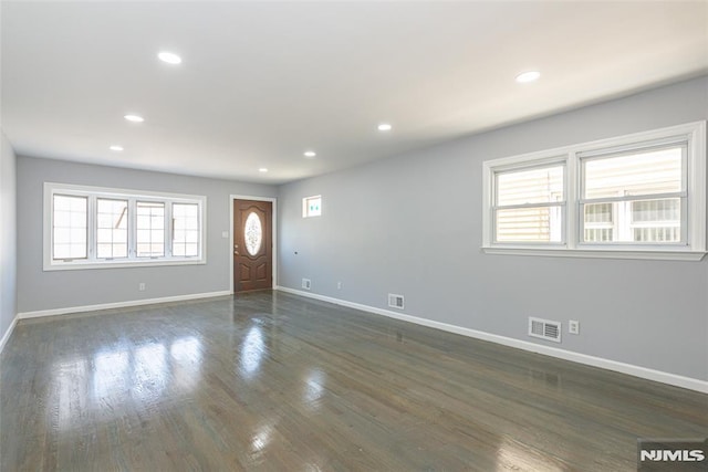 foyer featuring a healthy amount of sunlight, baseboards, visible vents, and dark wood-type flooring