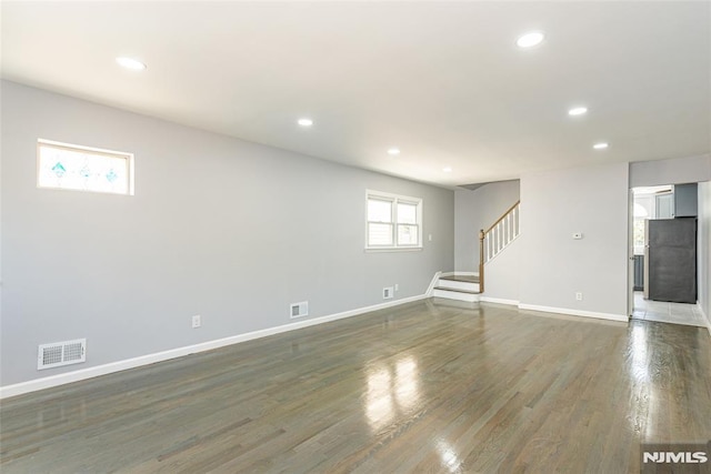 interior space with stairs, dark wood-type flooring, visible vents, and baseboards