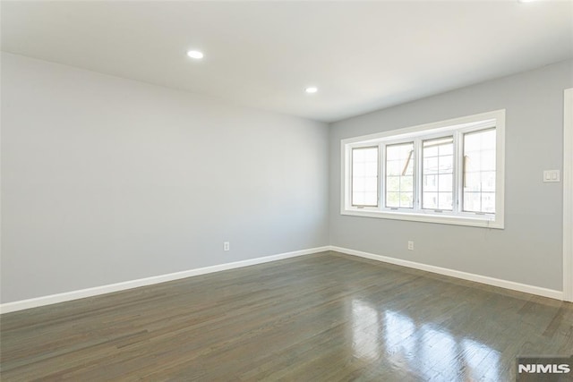 spare room with baseboards, dark wood-style flooring, and recessed lighting