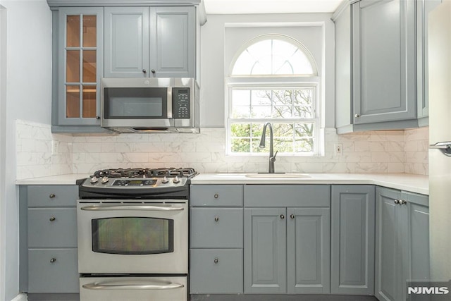 kitchen featuring decorative backsplash, appliances with stainless steel finishes, gray cabinets, and a sink