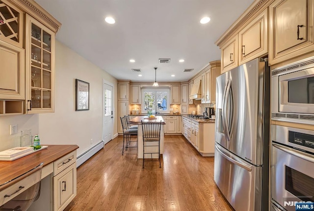 kitchen with cream cabinetry, light wood-style flooring, stainless steel appliances, and a baseboard heating unit