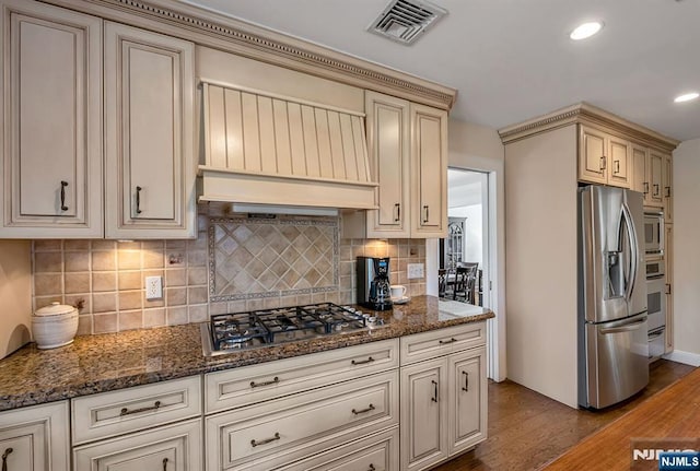 kitchen with visible vents, stainless steel appliances, custom range hood, cream cabinets, and light wood-type flooring