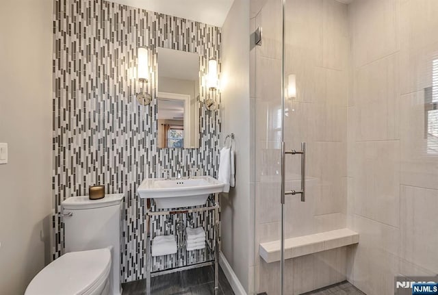 full bathroom with toilet, a stall shower, a sink, backsplash, and tile walls