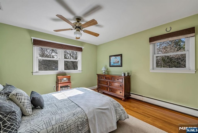 bedroom featuring visible vents, baseboard heating, wood finished floors, and a ceiling fan