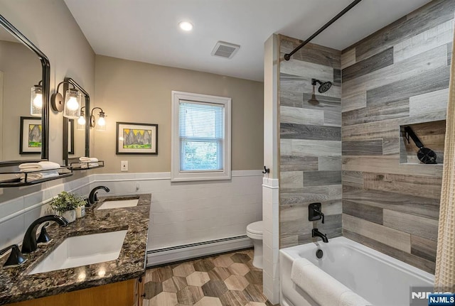 full bath featuring tile walls, visible vents, baseboard heating, and a sink