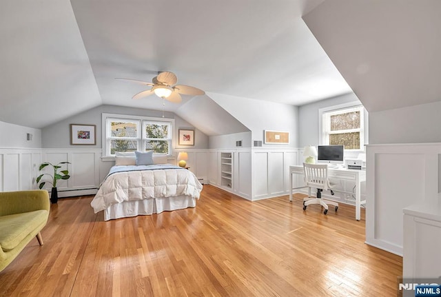 bedroom with light wood-style flooring, wainscoting, a baseboard radiator, lofted ceiling, and baseboard heating