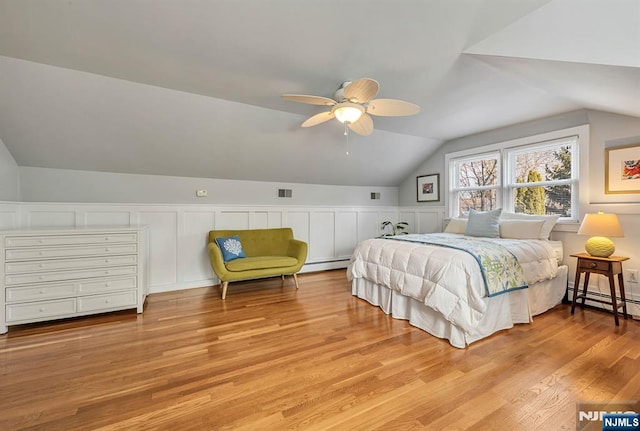 bedroom with vaulted ceiling, a baseboard heating unit, visible vents, and wood finished floors