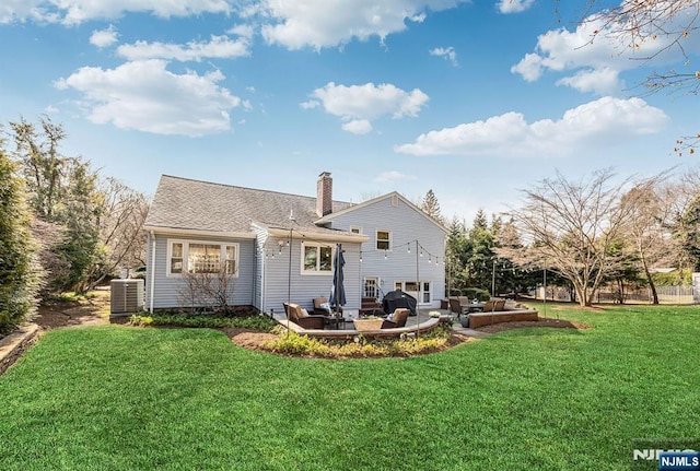 rear view of house featuring a patio, central AC, a shingled roof, a chimney, and a lawn