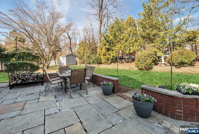 view of patio / terrace with outdoor dining space, a storage shed, and an outbuilding