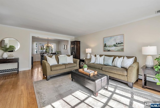 living room with visible vents, light wood-style floors, an inviting chandelier, and ornamental molding