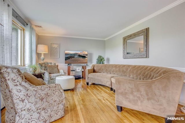 living room with visible vents, ornamental molding, and wood finished floors