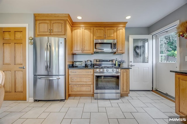 kitchen with appliances with stainless steel finishes, dark stone countertops, and recessed lighting