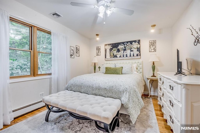 bedroom featuring a baseboard heating unit, visible vents, ceiling fan, and light wood finished floors