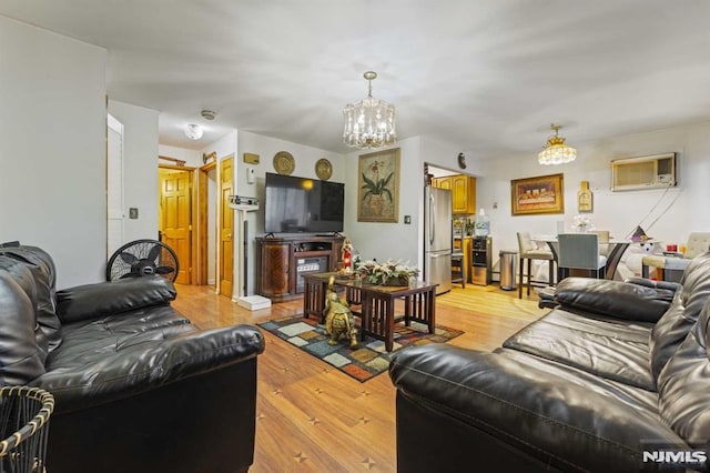 living area with a chandelier, light wood-style flooring, and a wall mounted AC