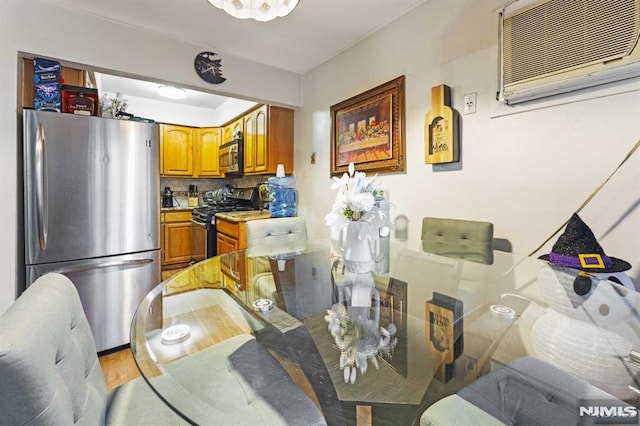 dining room with a wall mounted AC and light wood-style flooring