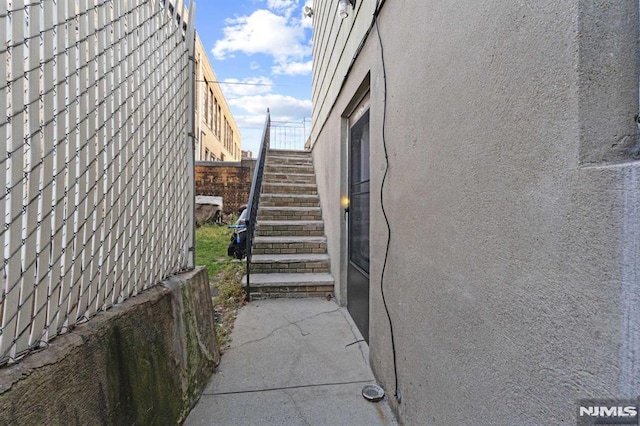 view of home's exterior featuring stairs, fence, and stucco siding