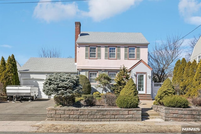 view of front of house featuring an attached garage, a chimney, aphalt driveway, and stucco siding