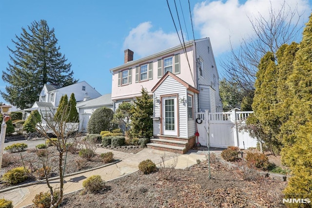 view of front of property featuring a garage, entry steps, fence, and a chimney