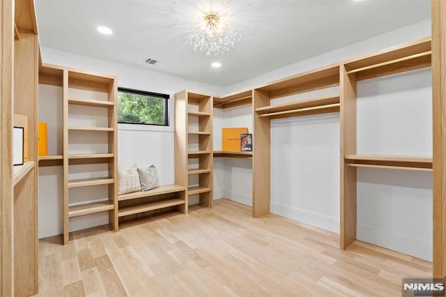 spacious closet featuring a notable chandelier, visible vents, and wood finished floors