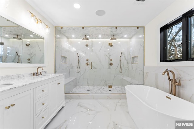 bathroom featuring marble finish floor, a marble finish shower, a freestanding tub, and a sink