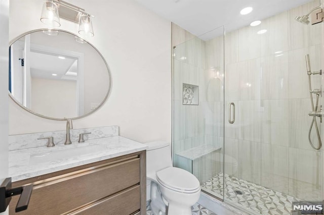 bathroom with toilet, a shower stall, and vanity