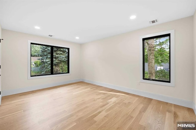 spare room featuring baseboards, a wealth of natural light, visible vents, and light wood-style floors