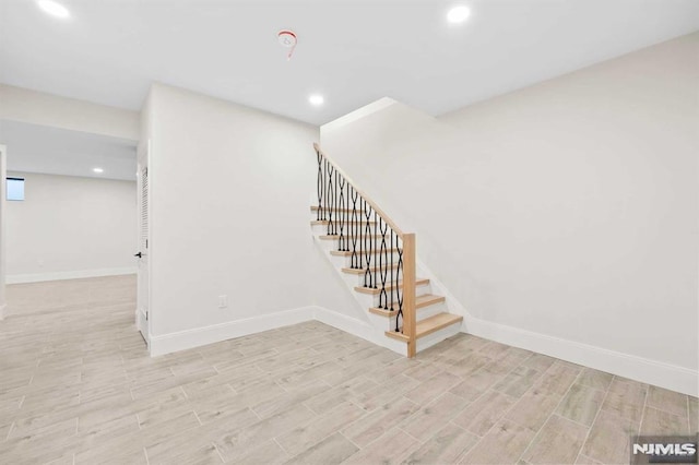 finished below grade area with wood finish floors, recessed lighting, baseboards, and stairs