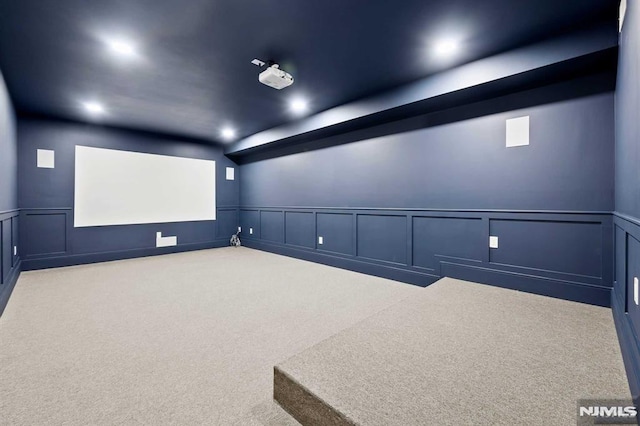 home theater room with a wainscoted wall, a decorative wall, and carpet flooring