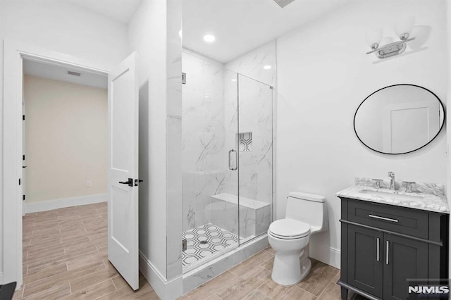 bathroom featuring vanity, a marble finish shower, toilet, and wood tiled floor