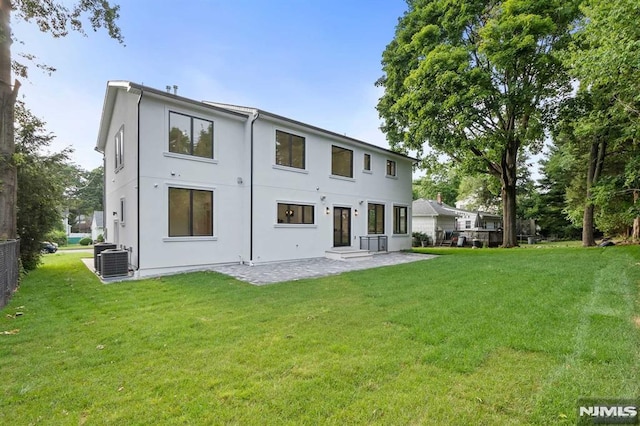 rear view of property with cooling unit, a yard, and a patio