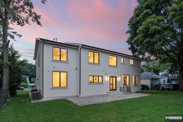 rear view of house with stucco siding, a lawn, a patio area, fence, and cooling unit