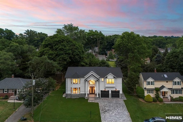 view of front of property with a garage, a front lawn, and decorative driveway