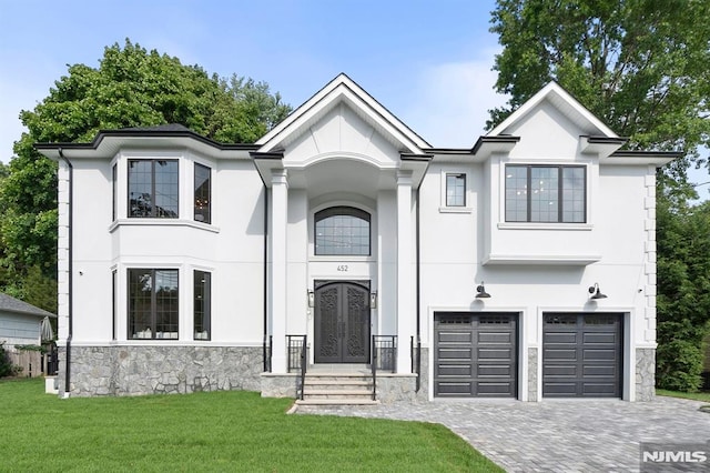 view of front facade with an attached garage, stone siding, decorative driveway, stucco siding, and a front lawn