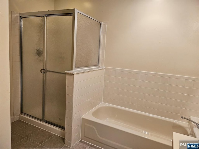 bathroom featuring a stall shower, a bath, and tile patterned floors