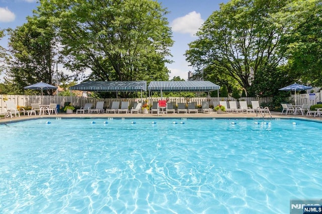 community pool with a patio area and fence