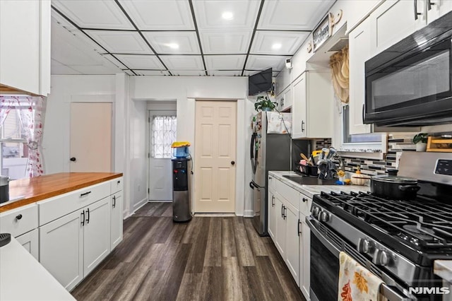 kitchen featuring appliances with stainless steel finishes, decorative backsplash, wood counters, and white cabinets