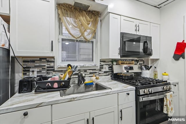 kitchen featuring black microwave, tasteful backsplash, white cabinetry, and stainless steel gas stove