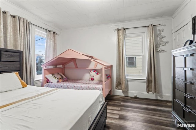 bedroom with dark wood-style floors, crown molding, and baseboards