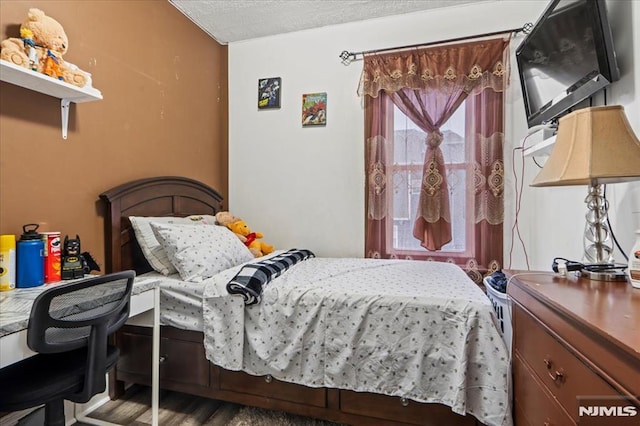 bedroom with a textured ceiling and wood finished floors