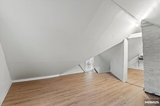 additional living space featuring vaulted ceiling, baseboards, and wood finished floors