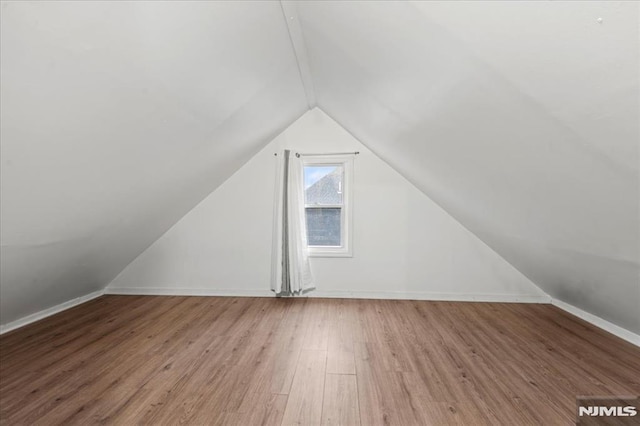 additional living space featuring lofted ceiling, baseboards, and wood finished floors