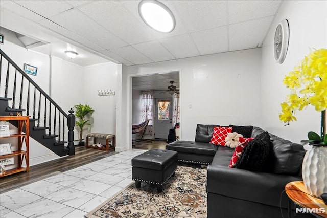 living area featuring marble finish floor, stairway, a paneled ceiling, and baseboards