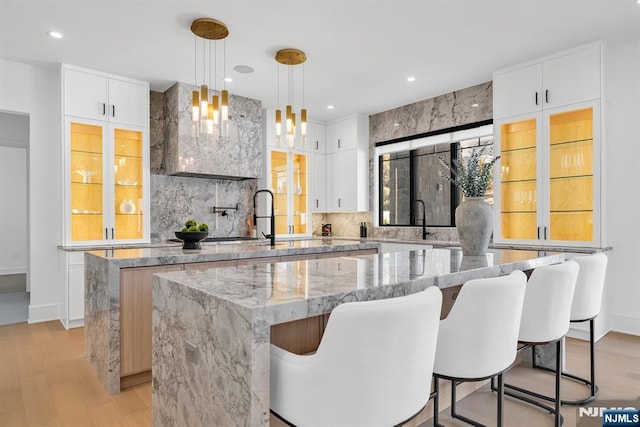 bar featuring decorative backsplash, decorative light fixtures, light wood-type flooring, a sink, and recessed lighting